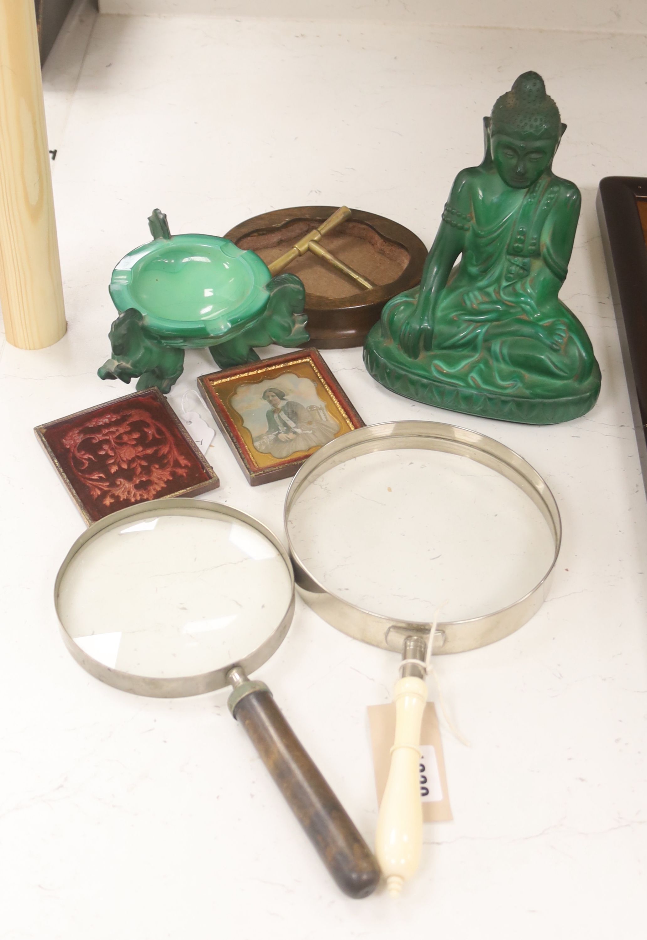 A French Art Deco green glass ashtray, a similar green glass Buddha, two magnifying glasses and a Daguerreotype portrait of a Victorian lady